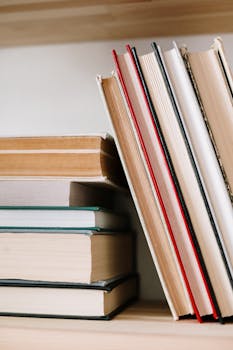 Close-up of assorted books stacked on a wooden bookshelf, symbolizing knowledge and learning.